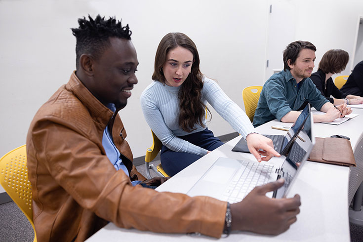 Heller students working together while looking at a computer