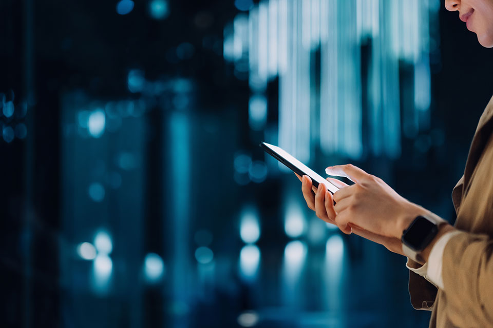 A person using their smartphone in front of a futuristic background.