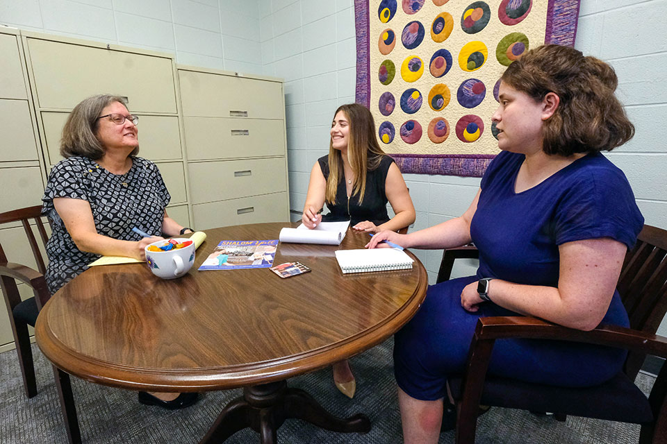 Lauren Balfour sits at a table with colleagues.