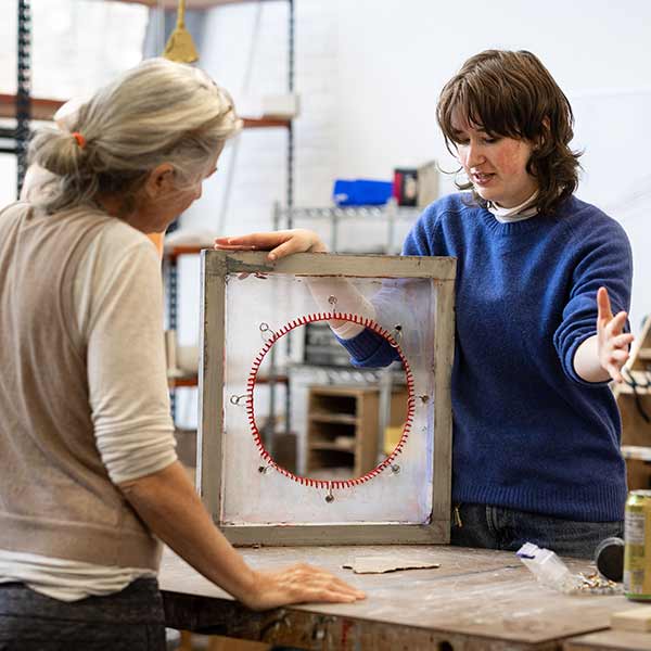 An art students shows a piece to a professor