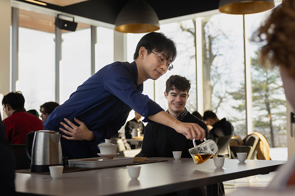 A student serving another student tea in a Tea Club meeting.