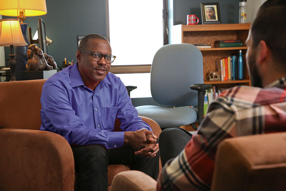A Brandeis counselor speaks with a student in an office.