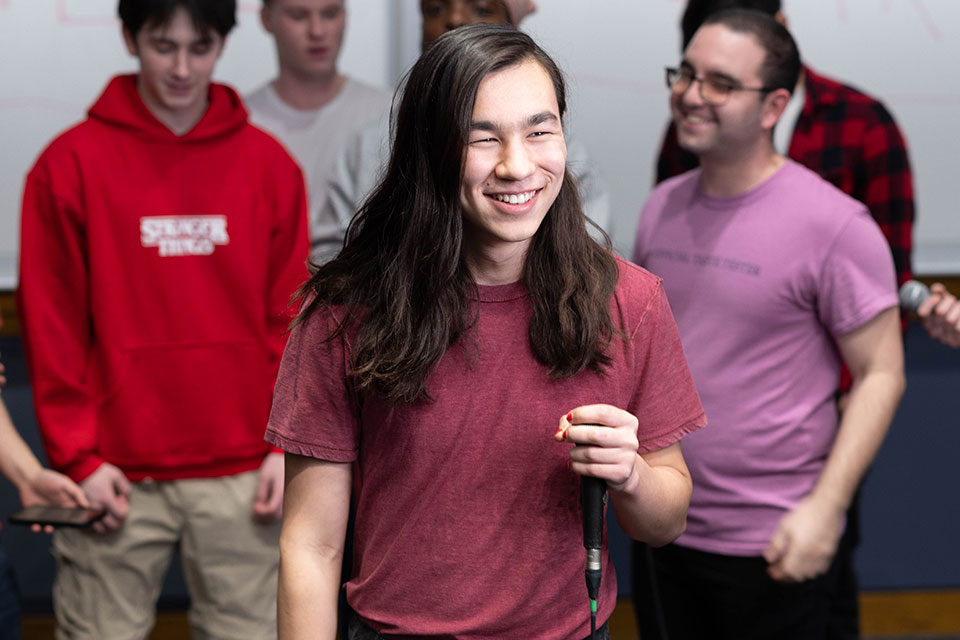A student smiling and holding a microphone