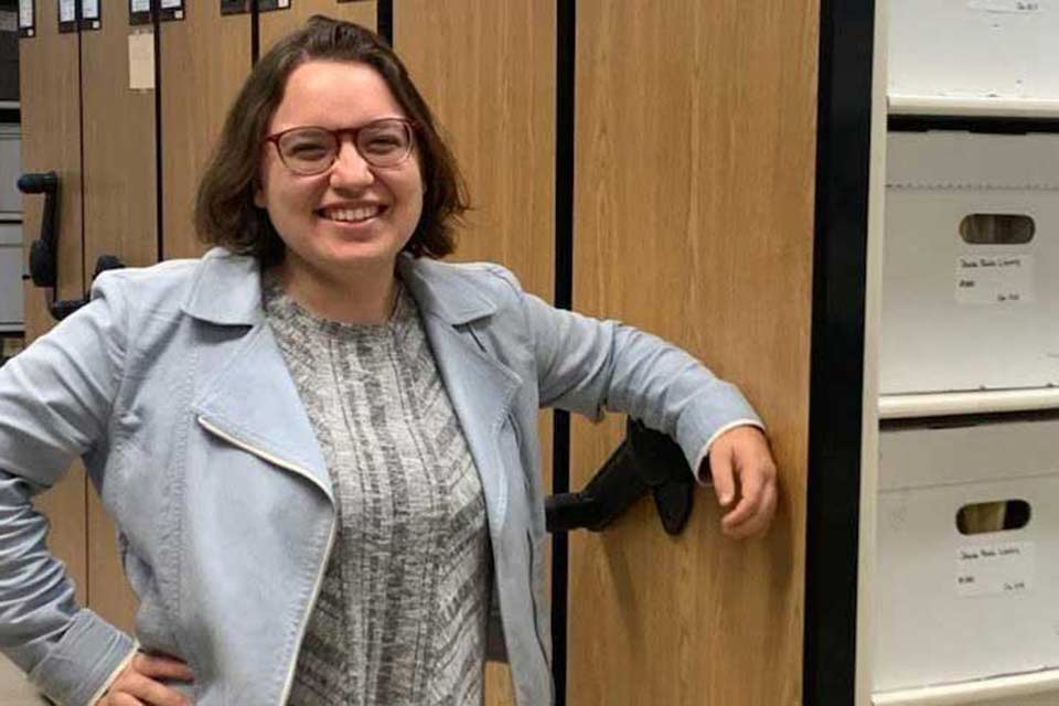 Dina standing near filing cabinets and smiling