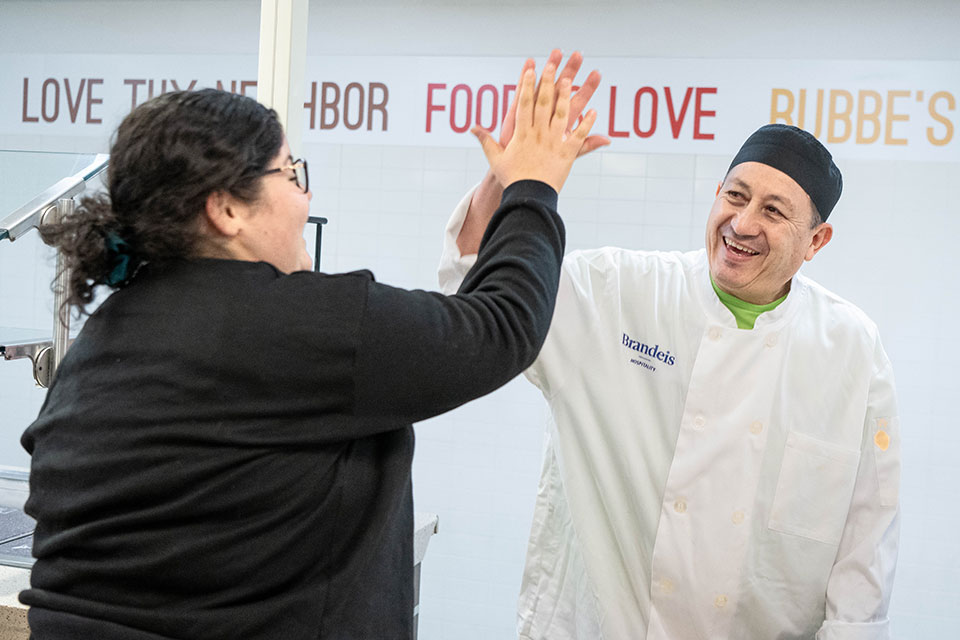 Two staff members high-five in a Brandeis dining hall