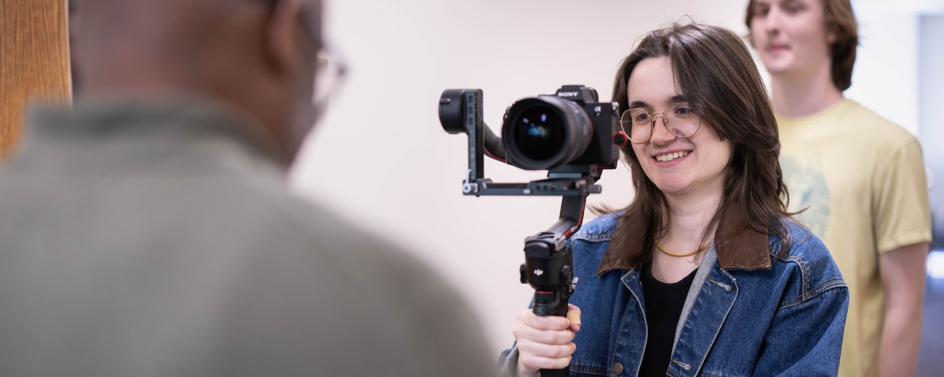 A student films another person with a video camera.
