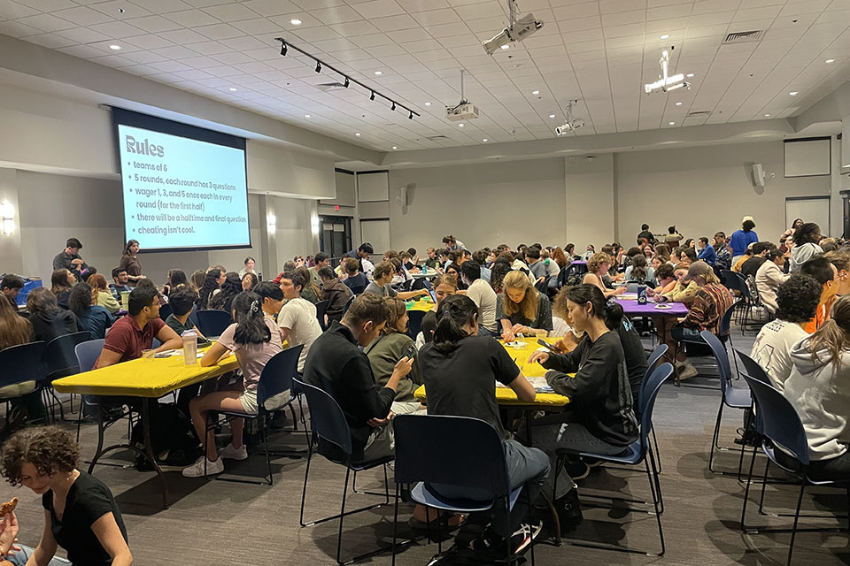 Students are sitting around tables playing trivia in teams