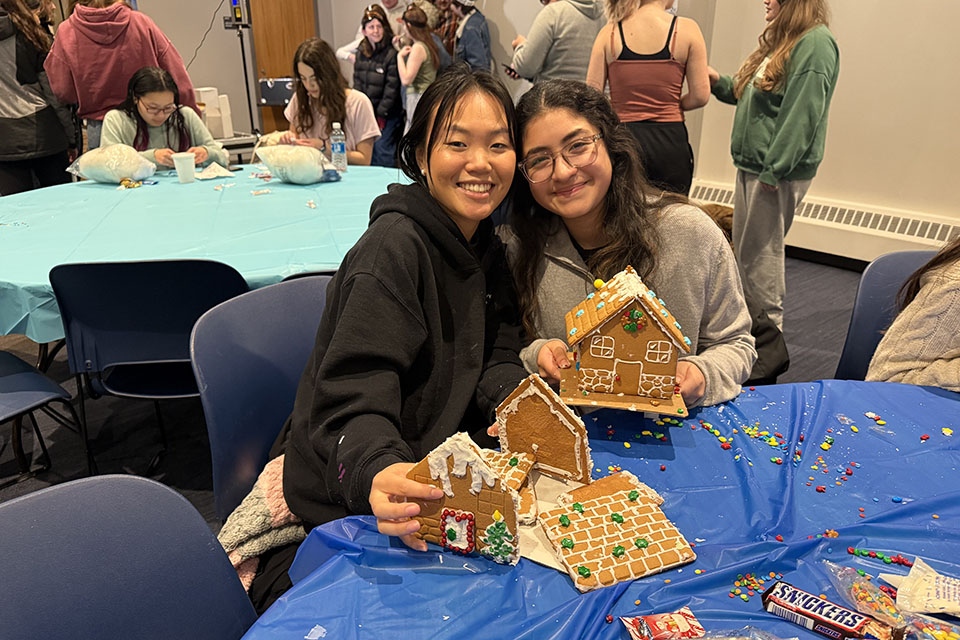 Two students pose with the gingerbread houses they decorated at the event.