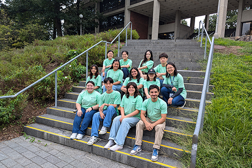 13 students sitting on a staircase wearing matching light green IREP shirts.