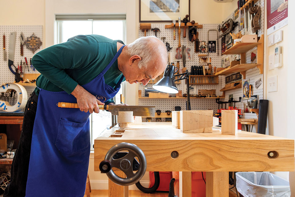 Harry Mairson cutting a piece of wood in his workshop.