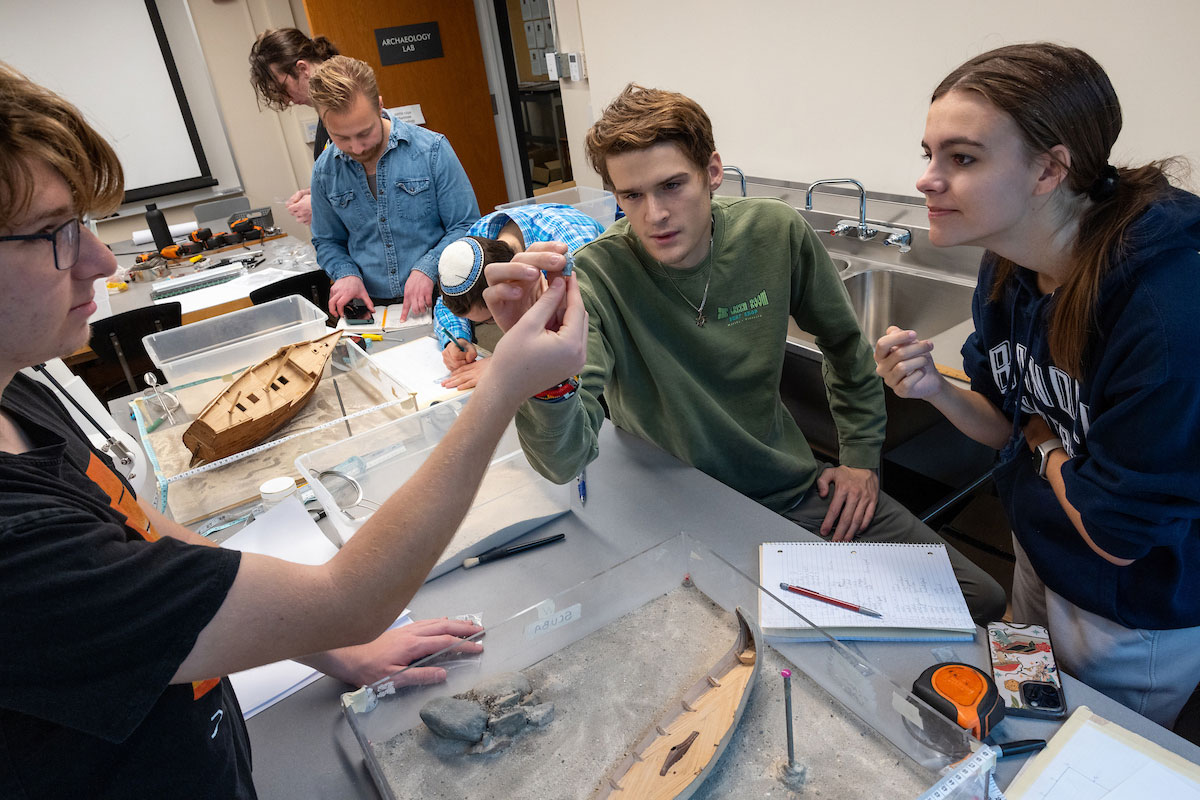 Students inspect a miniature artifact excavated from a model shipwreck