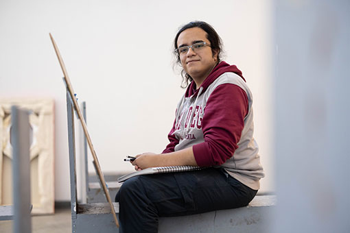 Samuel sits on a stool painting