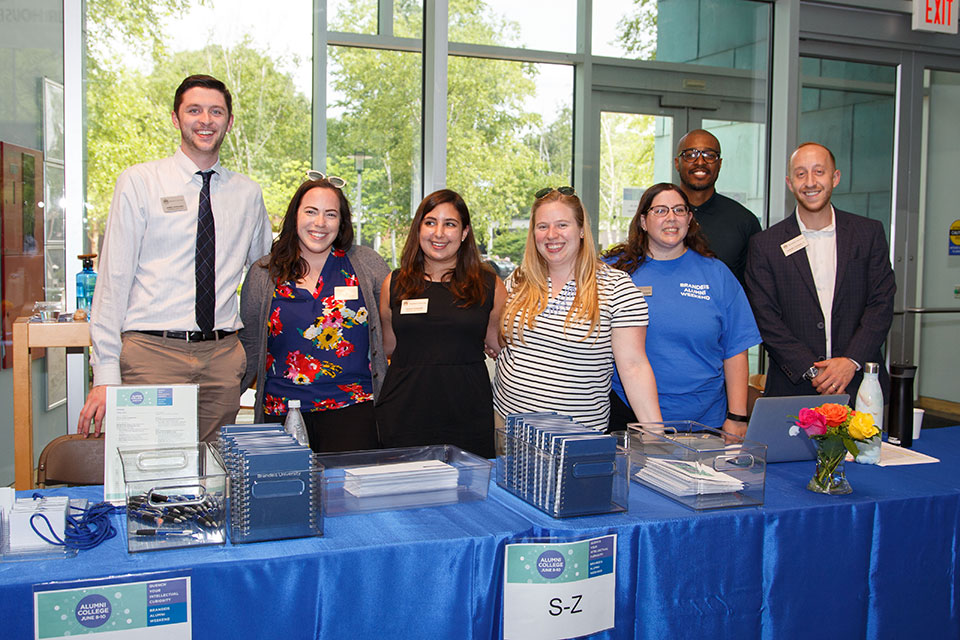 Brandeis staff stand around a table and smile